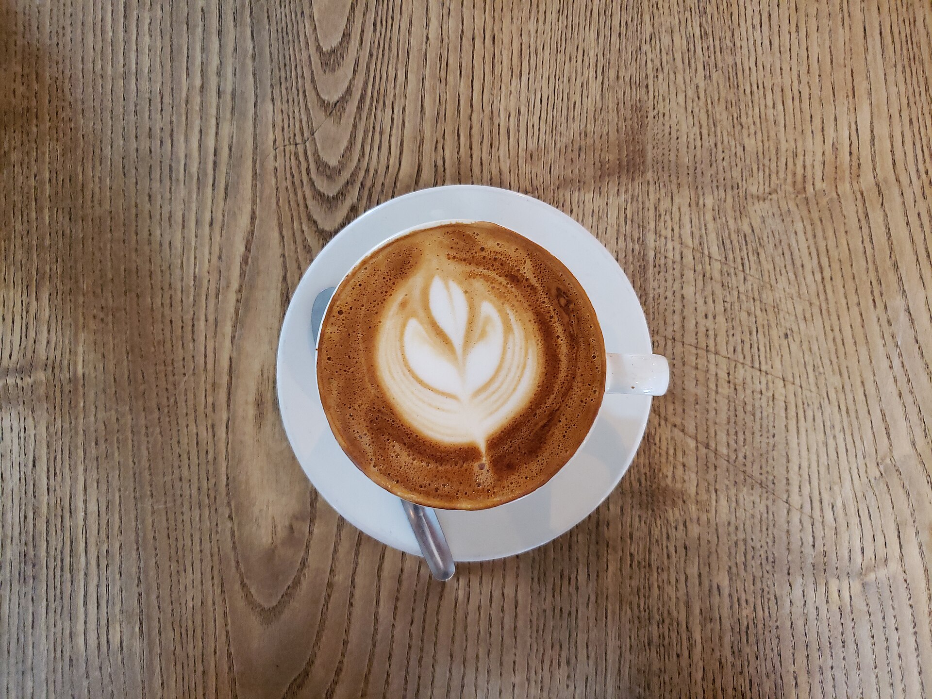 木のテーブルに置かれたラテアートのコーヒー